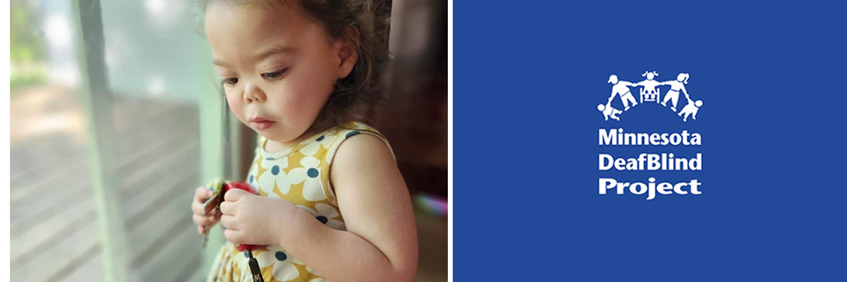 A Latina toddler girl is standing next to a glass door and looking down.